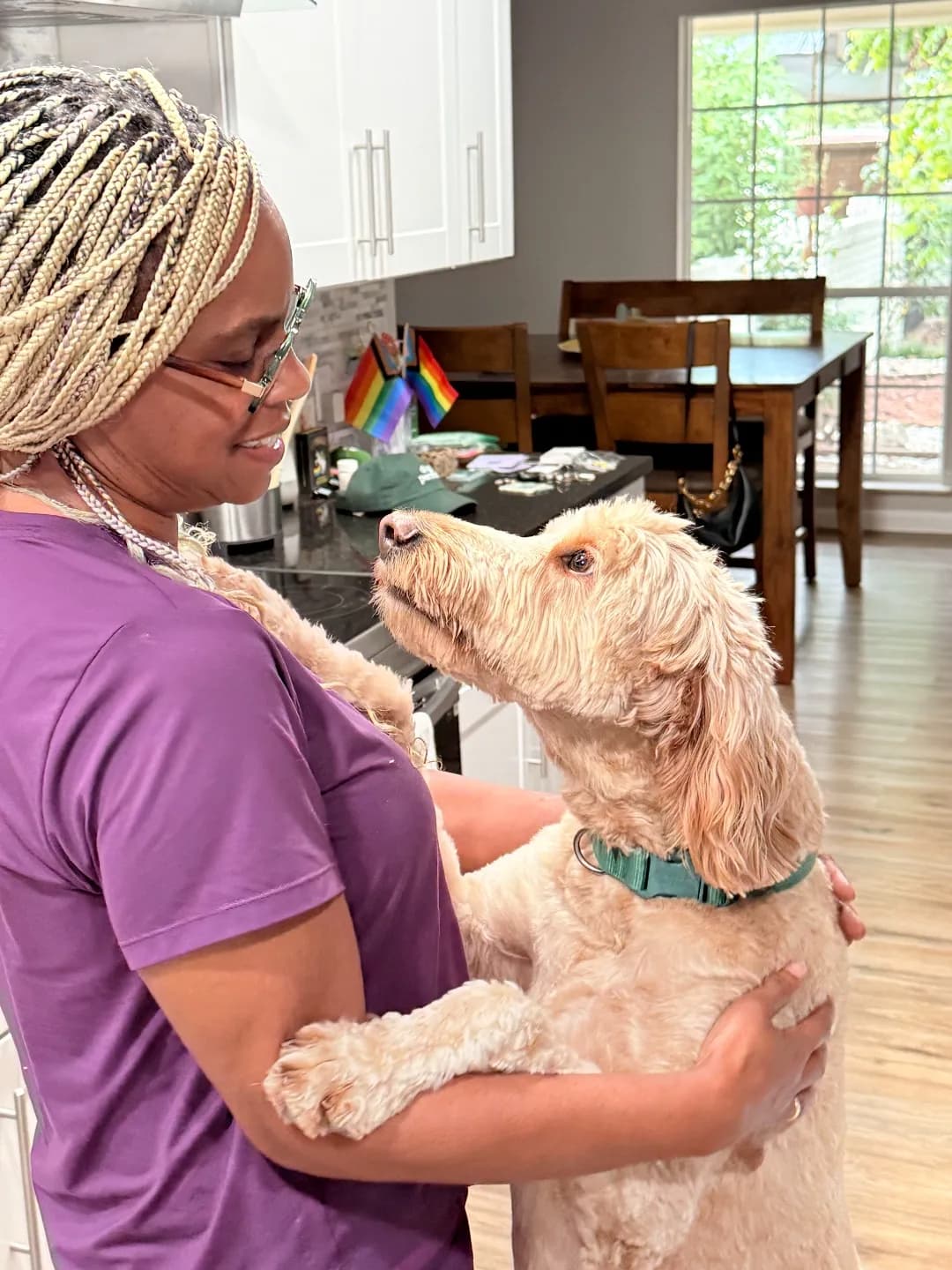 Jackye at home with a goldendoodle, wearing a Keep Waco Wagging tee